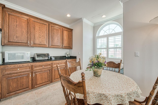 kitchen featuring light tile patterned floors, dark stone counters, and ornamental molding