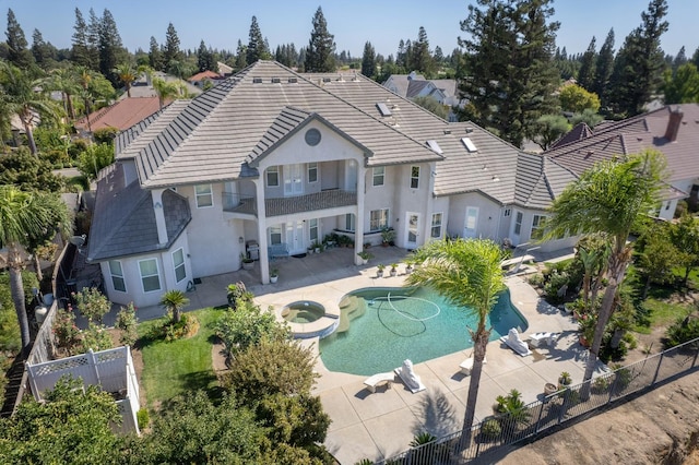 rear view of property with a patio and a swimming pool with hot tub