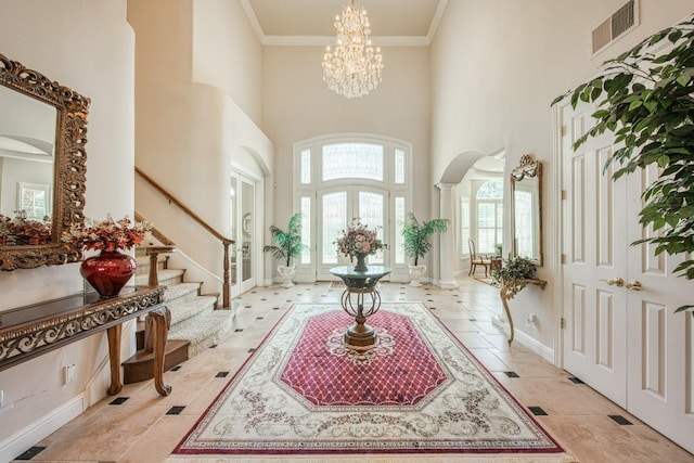 entryway with crown molding, a high ceiling, and an inviting chandelier