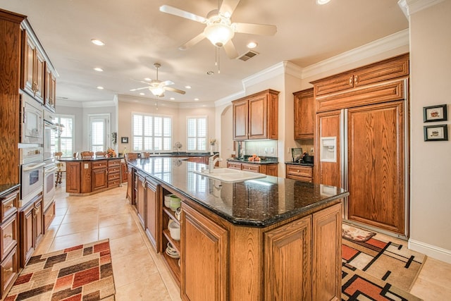 kitchen with crown molding, ceiling fan, sink, and a kitchen island with sink