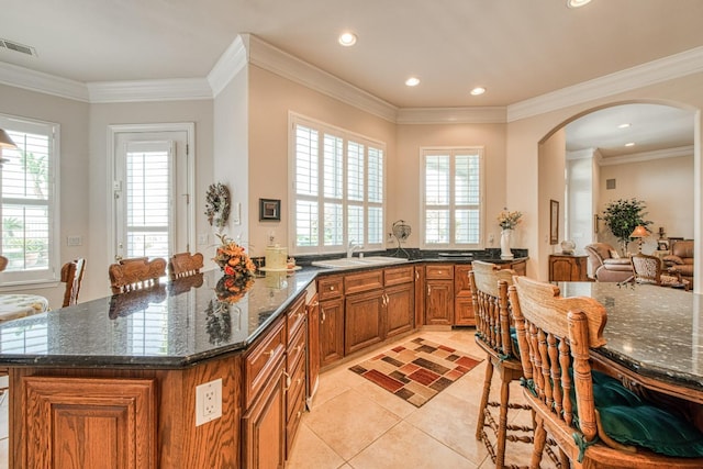 kitchen with dark stone countertops, crown molding, sink, and light tile patterned flooring