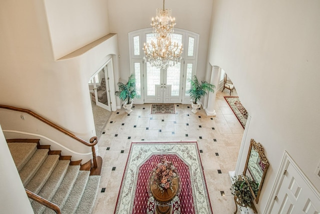 tiled foyer featuring french doors, an inviting chandelier, and a high ceiling