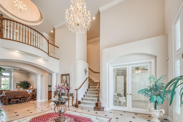 entrance foyer featuring a high ceiling, decorative columns, a notable chandelier, and ornamental molding