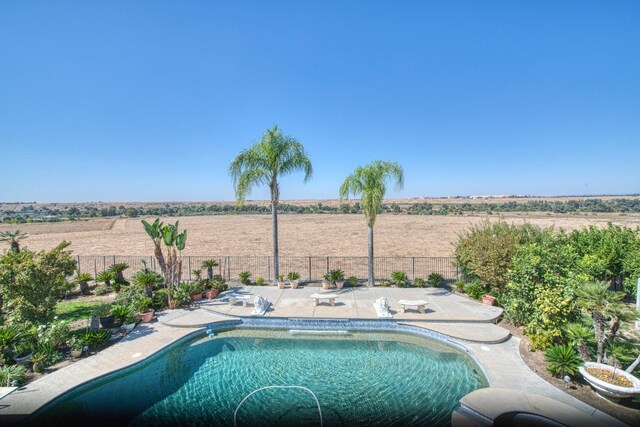 view of swimming pool featuring a rural view and a patio