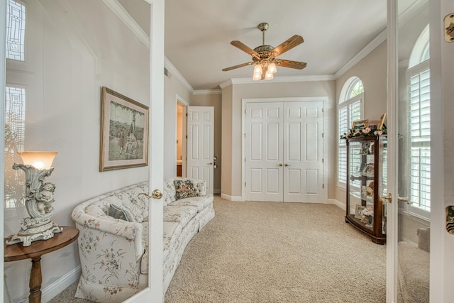 living area featuring crown molding, ceiling fan, and carpet flooring