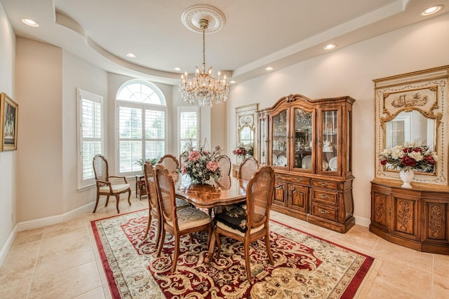 tiled dining space with a raised ceiling and an inviting chandelier