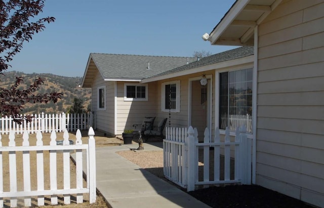 exterior space featuring roof with shingles and fence