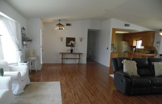 living area with lofted ceiling, wood finished floors, visible vents, and a healthy amount of sunlight