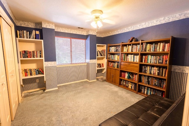 sitting room featuring a textured ceiling, light colored carpet, and ceiling fan