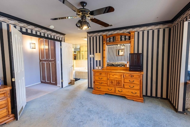 carpeted bedroom with ornamental molding, connected bathroom, and ceiling fan