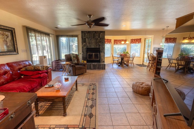 tiled living room featuring ceiling fan, a textured ceiling, and a tile fireplace