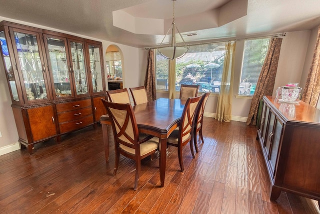 dining area with a tray ceiling and dark hardwood / wood-style flooring