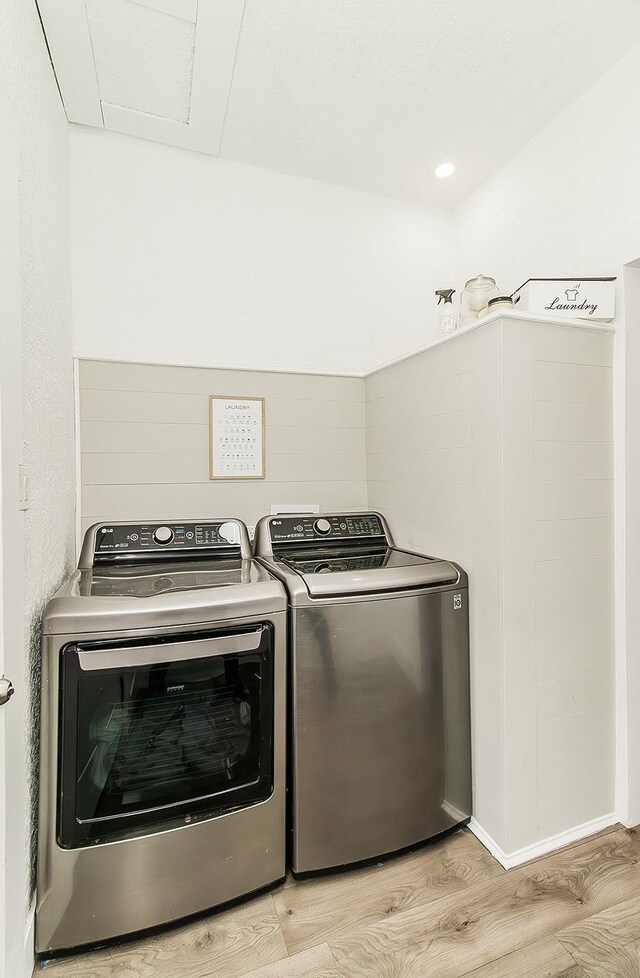 laundry room with laundry area, light wood finished floors, and washer and clothes dryer