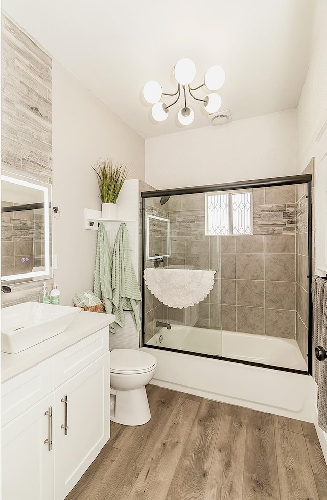 bathroom with shower / bath combination with glass door, vanity, toilet, and wood finished floors