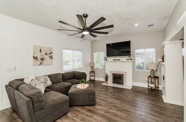 living room featuring dark wood-type flooring, a brick fireplace, and a wealth of natural light