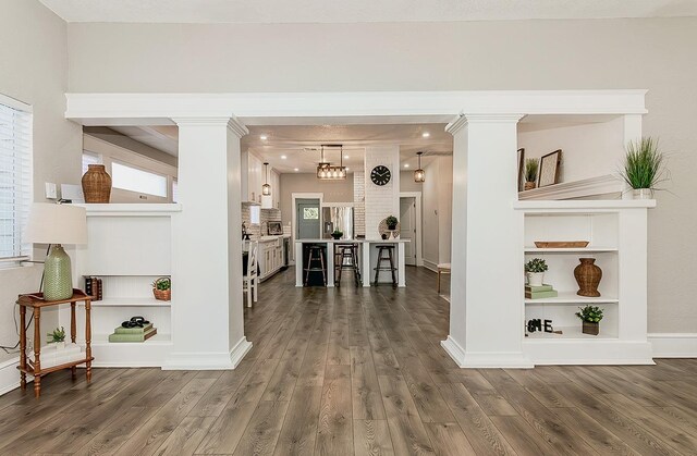 interior space featuring ornate columns, baseboards, and dark wood-style floors