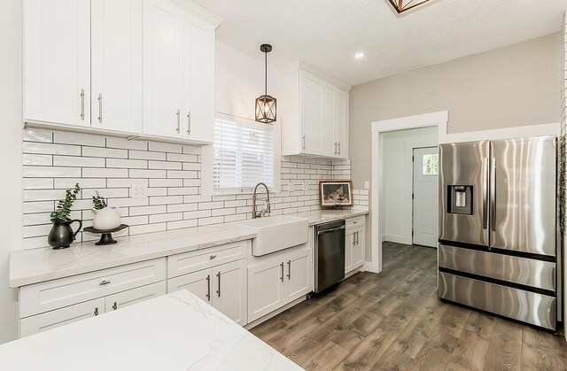 kitchen featuring stainless steel appliances, white cabinets, hanging light fixtures, and a sink