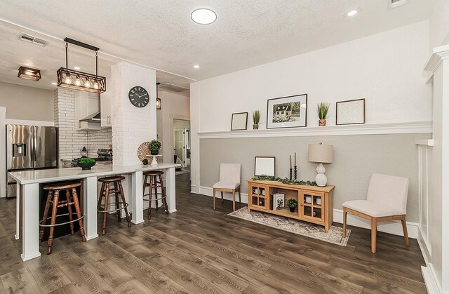 sitting room featuring dark wood-style floors, a textured ceiling, and visible vents