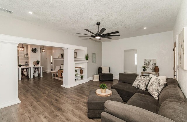 living room with a textured ceiling, recessed lighting, visible vents, a ceiling fan, and dark wood finished floors