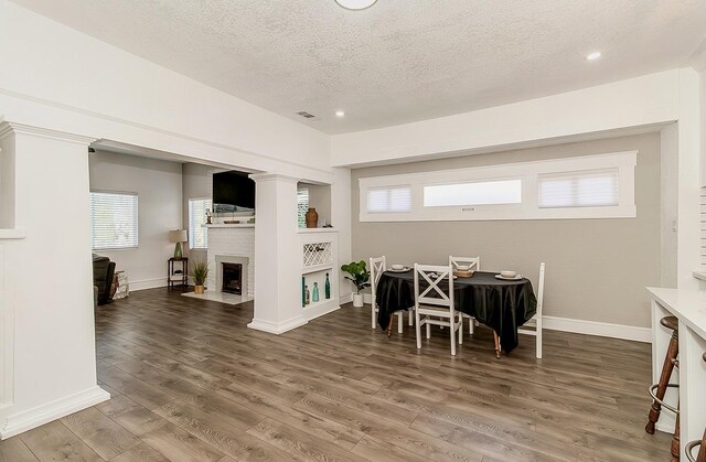 dining area featuring dark wood-style floors, plenty of natural light, a fireplace, and visible vents