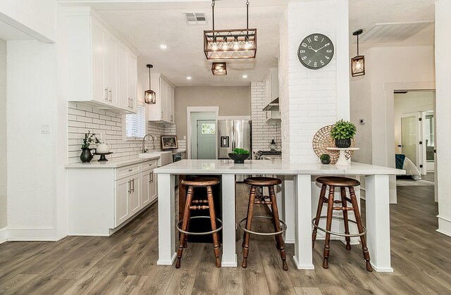 kitchen featuring visible vents, light countertops, stainless steel refrigerator with ice dispenser, and white cabinetry