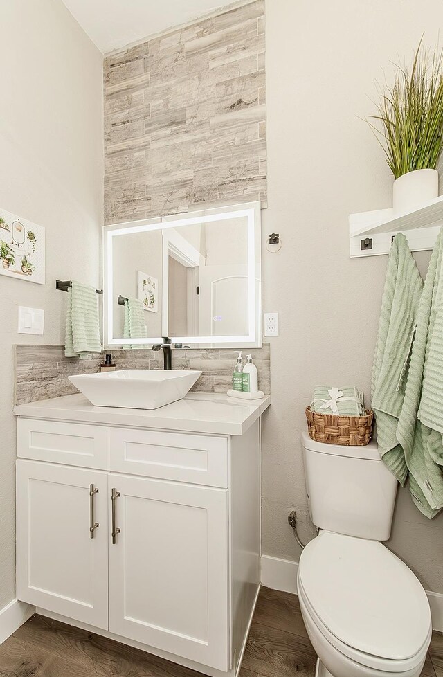 bathroom with toilet, baseboards, wood finished floors, and vanity