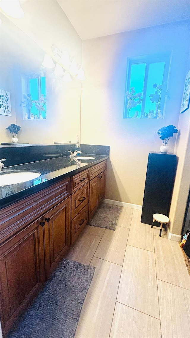 bathroom featuring a sink, baseboards, and double vanity