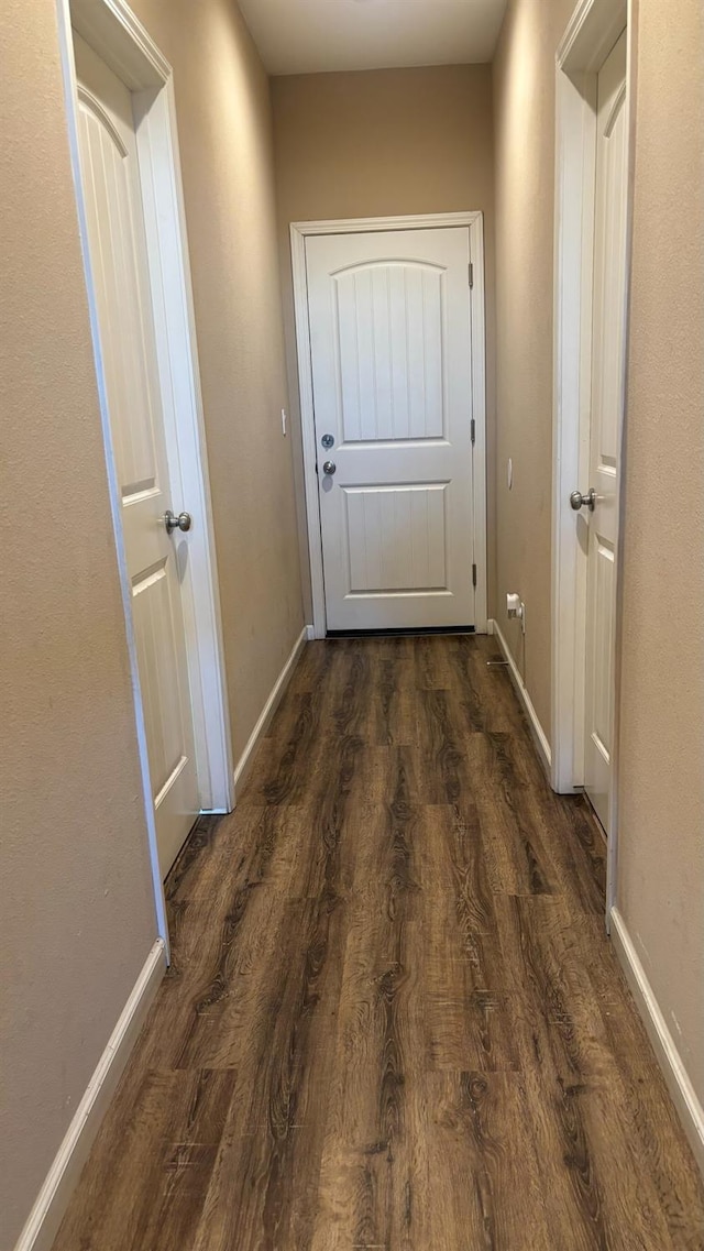 hallway with dark wood finished floors and baseboards