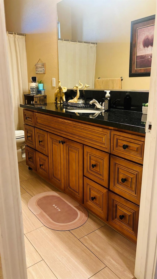 full bath with tile patterned flooring, vanity, and toilet