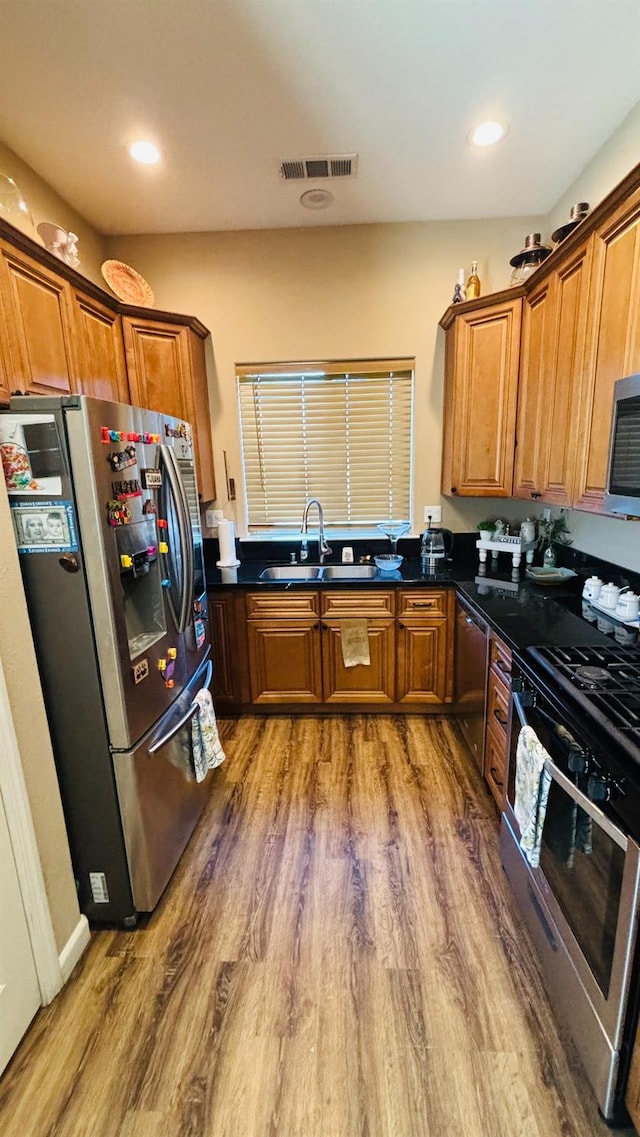 kitchen with appliances with stainless steel finishes, brown cabinetry, a sink, and visible vents