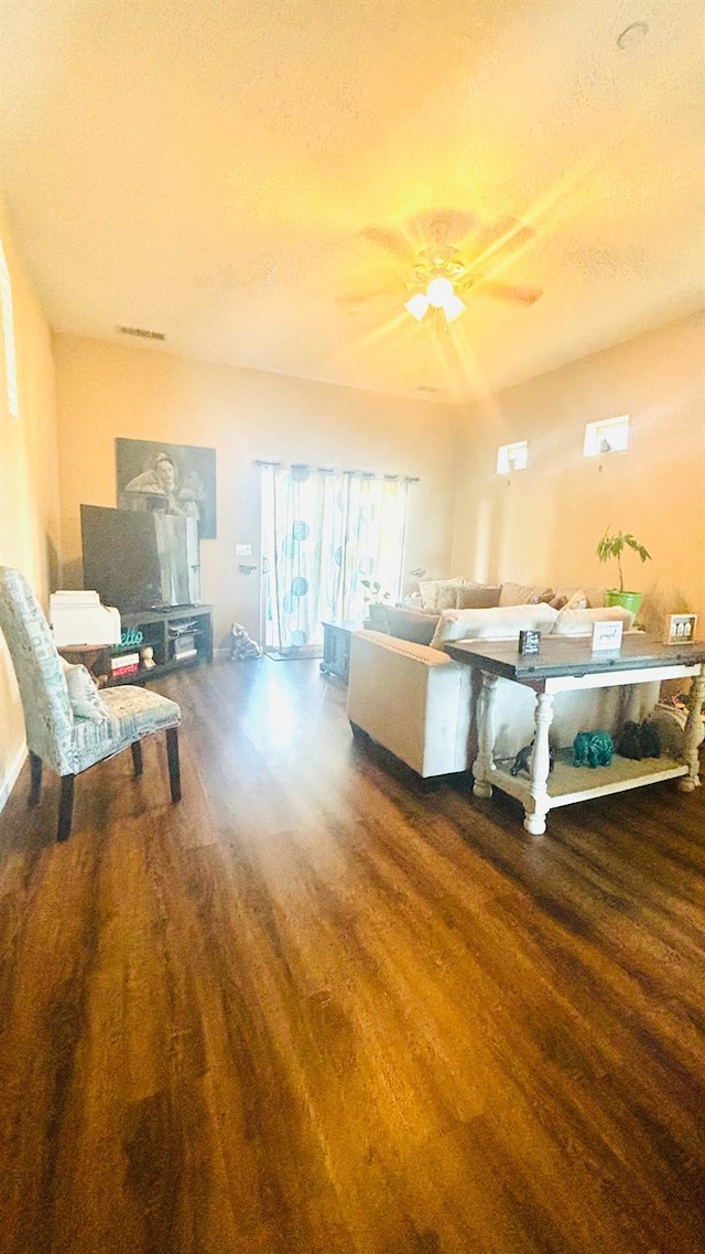 living room featuring ceiling fan, a textured ceiling, wood finished floors, and visible vents