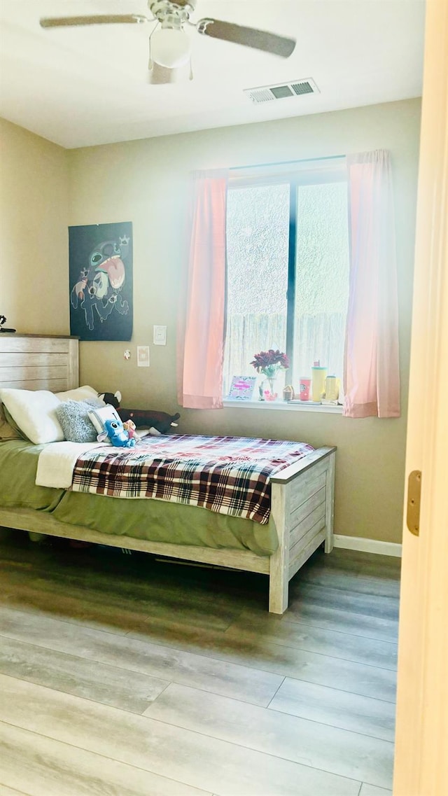 unfurnished bedroom featuring visible vents, ceiling fan, baseboards, and wood finished floors