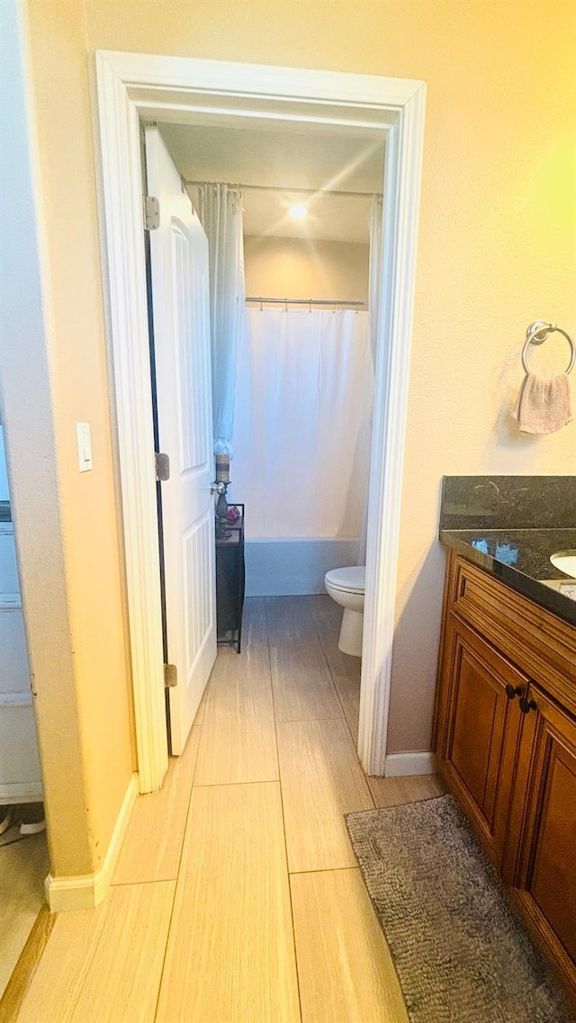 bathroom featuring curtained shower, vanity, toilet, and baseboards