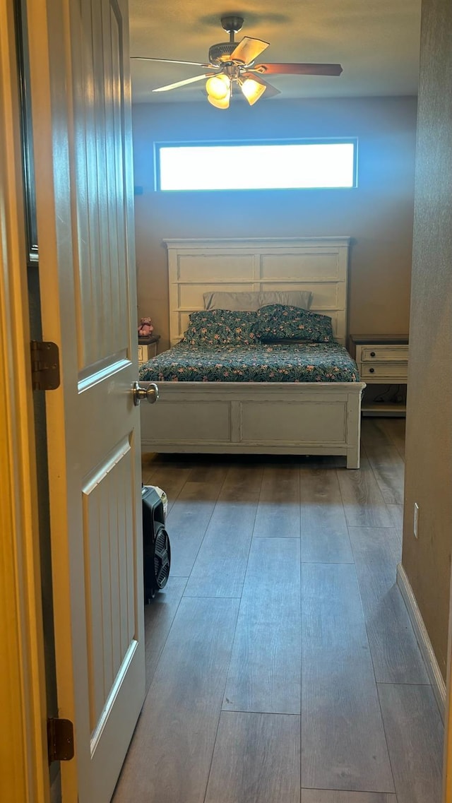 bedroom featuring multiple windows, wood finished floors, and a ceiling fan