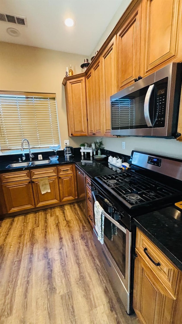 kitchen with stainless steel appliances, light wood-type flooring, visible vents, and brown cabinets