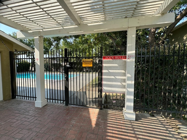 view of gate with fence, a pergola, and a fenced in pool