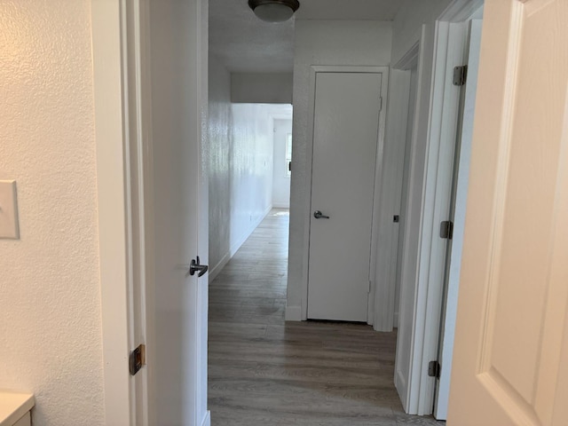 hallway featuring a textured wall and wood finished floors