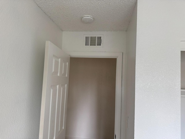 hallway with visible vents and a textured ceiling