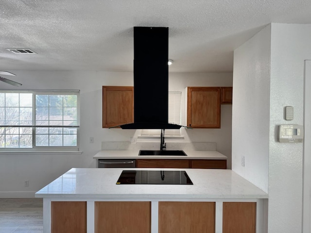 kitchen featuring brown cabinets, visible vents, stainless steel dishwasher, a sink, and black electric cooktop