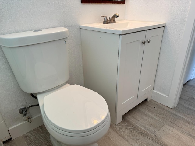 half bathroom with toilet and wood finished floors