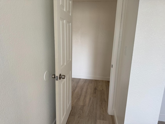 corridor featuring baseboards and wood finished floors