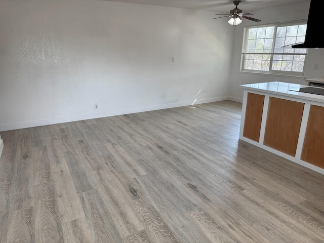 interior space featuring ceiling fan, light wood-style flooring, and baseboards