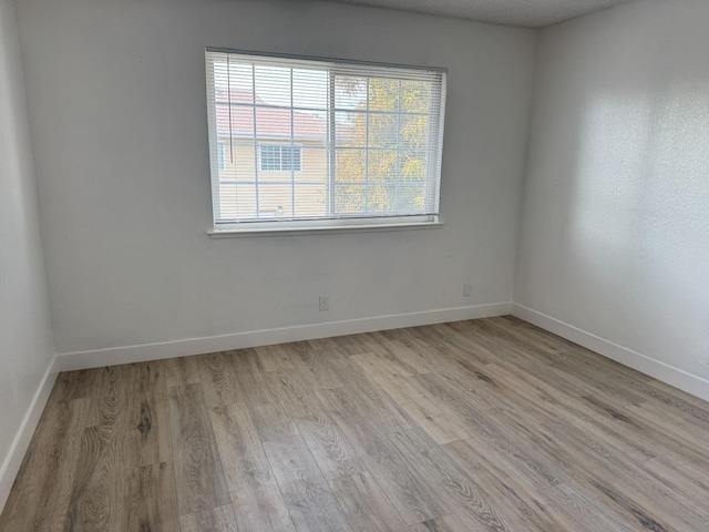 unfurnished room with baseboards and light wood finished floors