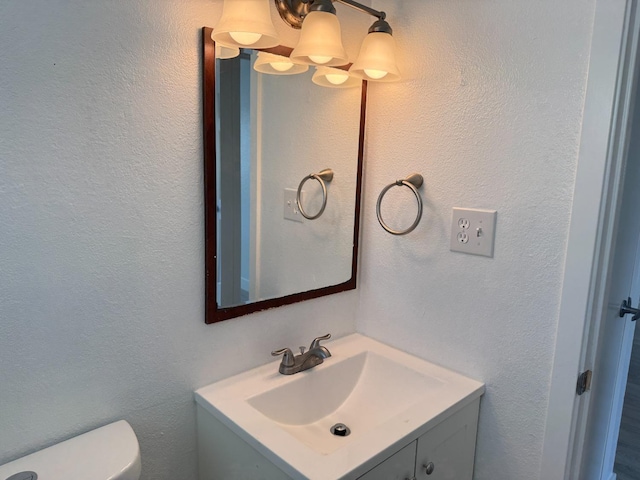 half bath featuring toilet, a textured wall, and vanity