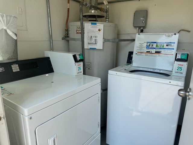 clothes washing area featuring water heater and washer and clothes dryer