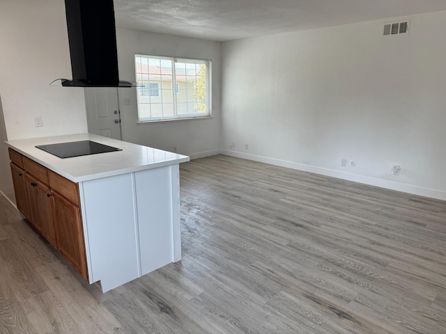 2216 Peach Ave Unit 4, Clovis, CA 93612 - kitchen with black electric cooktop, extractor fan, light wood finished floors, light countertops, and brown cabinetry