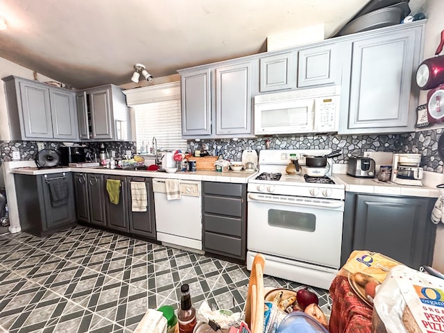 kitchen with decorative backsplash, white appliances, and gray cabinets