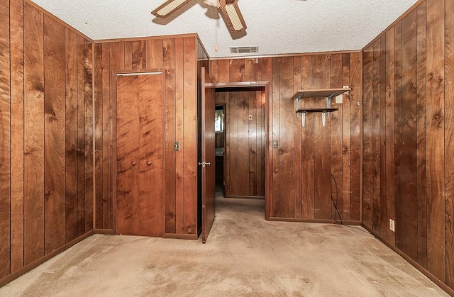 interior space with wood walls, ceiling fan, and a textured ceiling