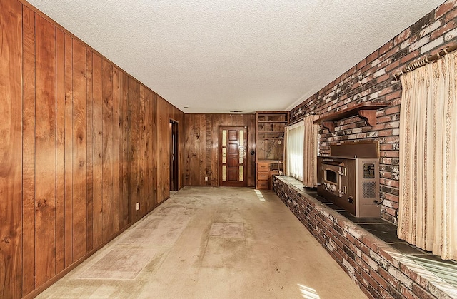 unfurnished living room featuring a fireplace, a textured ceiling, and wooden walls