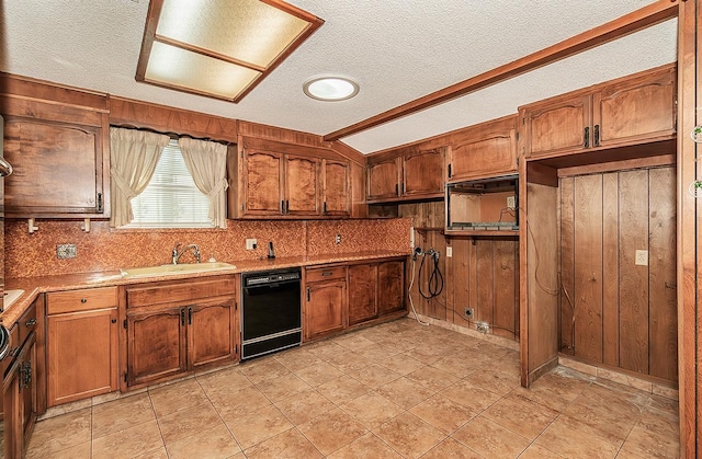 kitchen featuring a textured ceiling, wood walls, sink, and black dishwasher